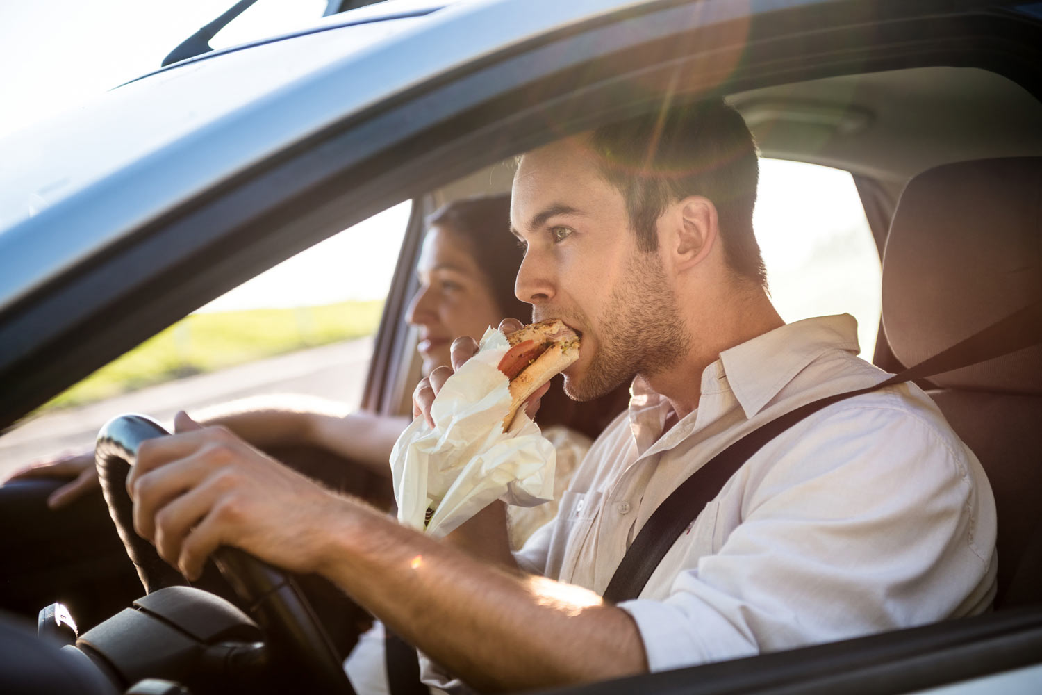 Couple in Car - Driver Eating while Behind the Wheel