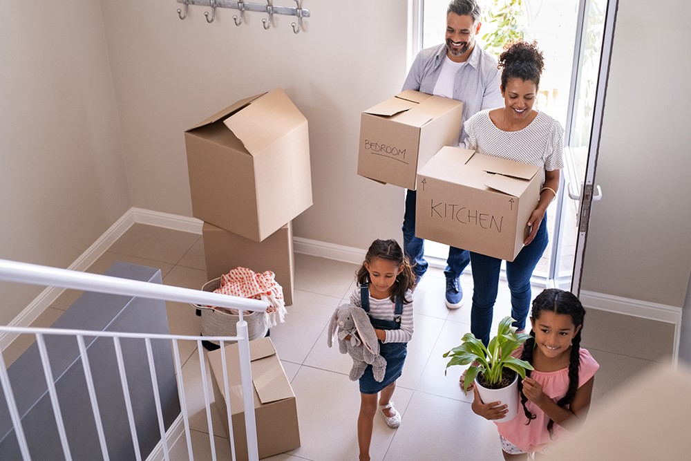 A family holding boxes at the entrance of a home.