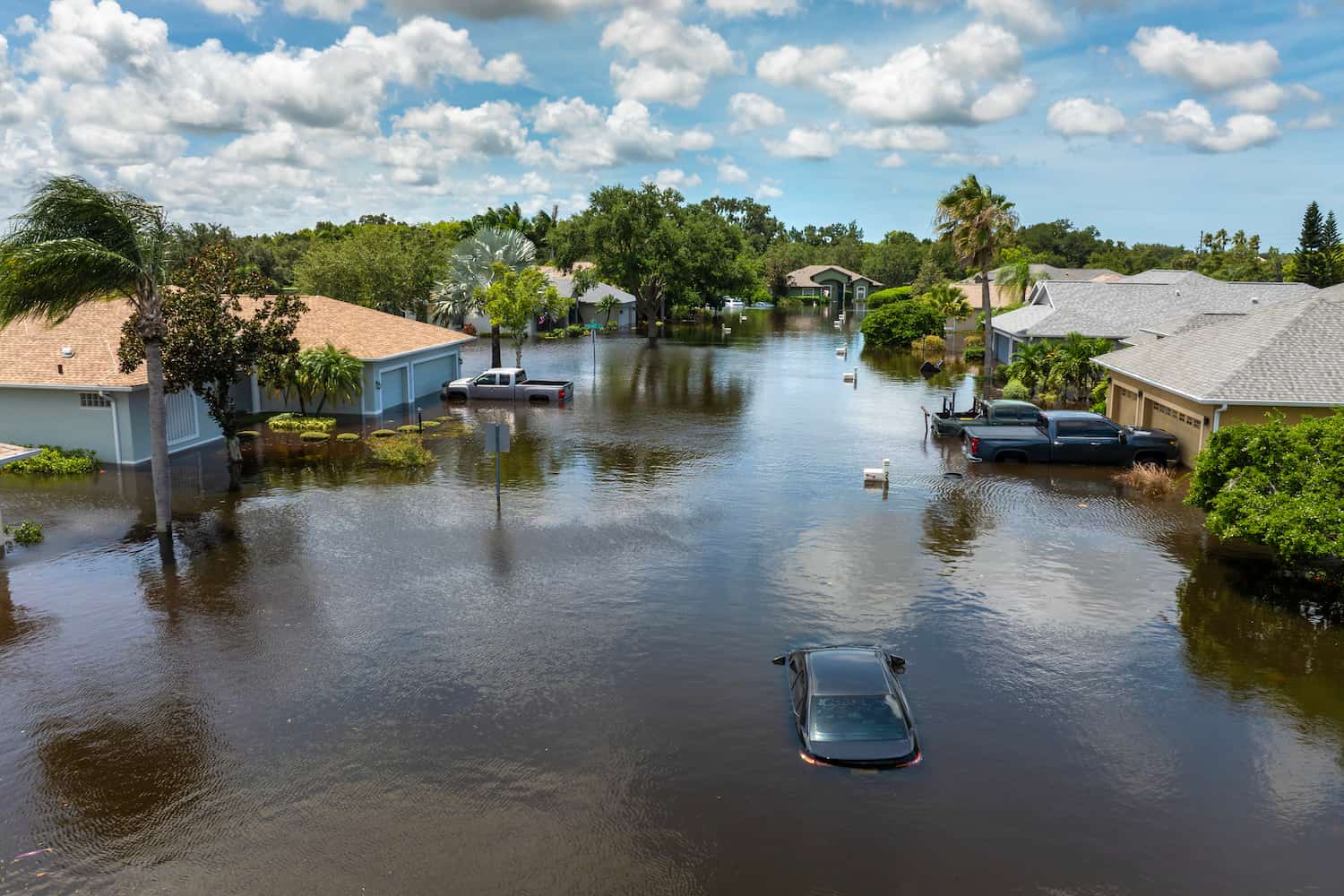 Car partially submerged on a flooded residential street after a major storm.