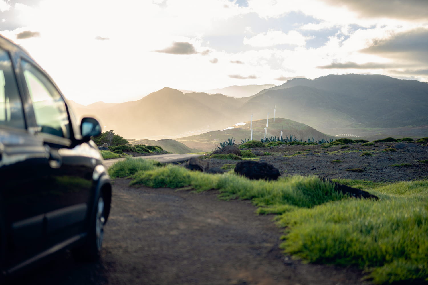 Evening glow on coastal turbines and a roadside car.