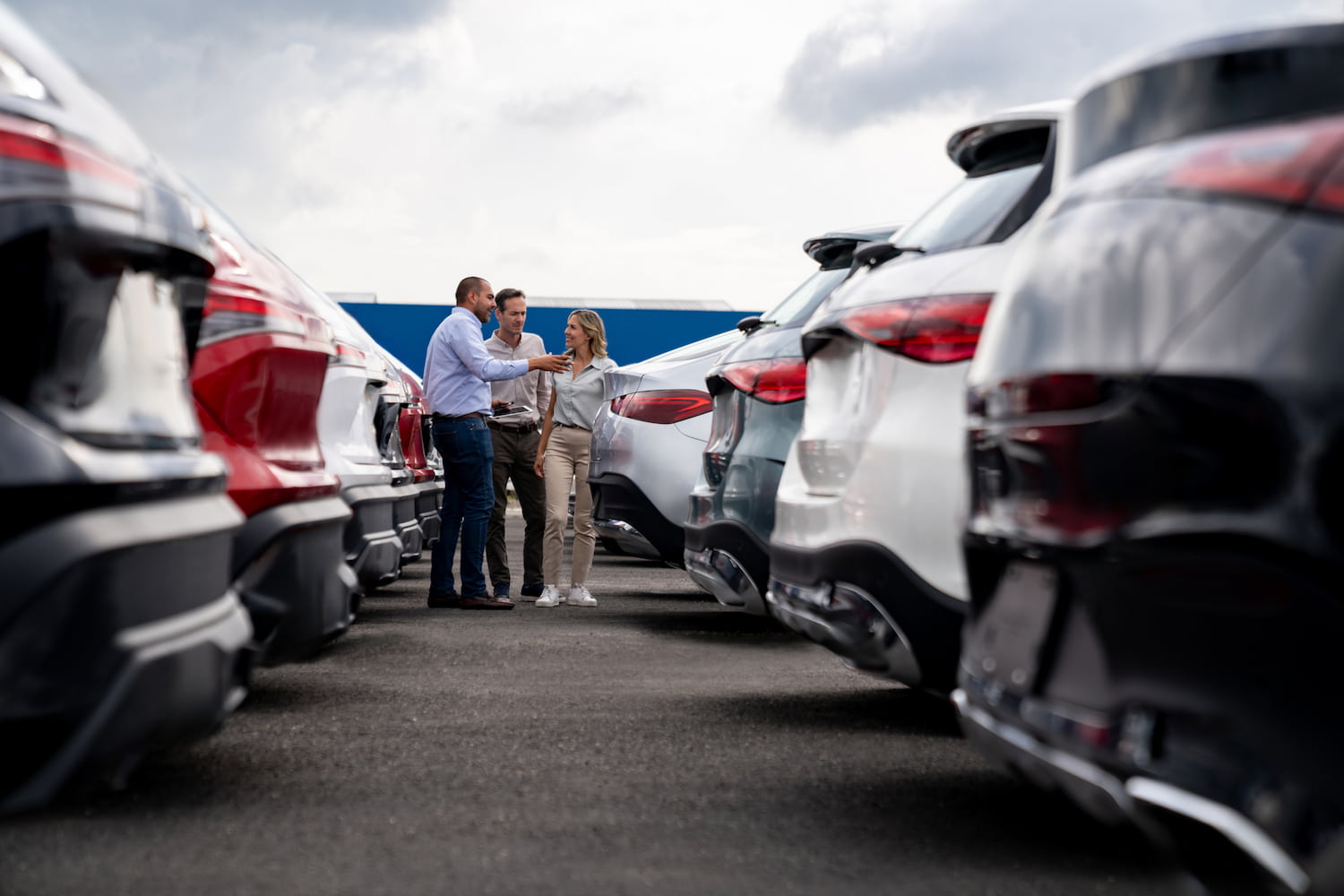 Car salesperson showing cars to a couple shopping at the dealership.