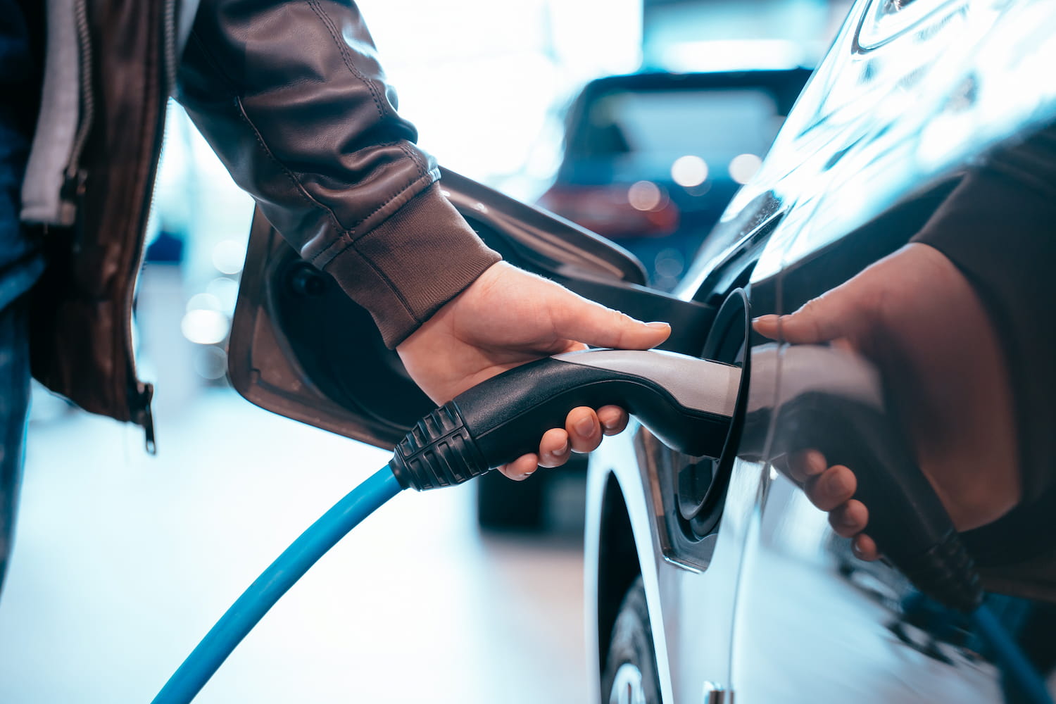 Close-up of a hand holding an electric car charging connector.