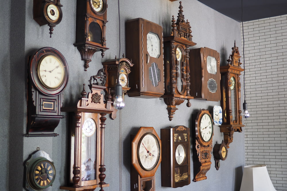 Collectible clocks made of brown wood are mounted on the wall.