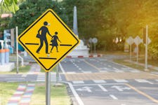 School zone sign on blur traffic road with colorful abstract background.