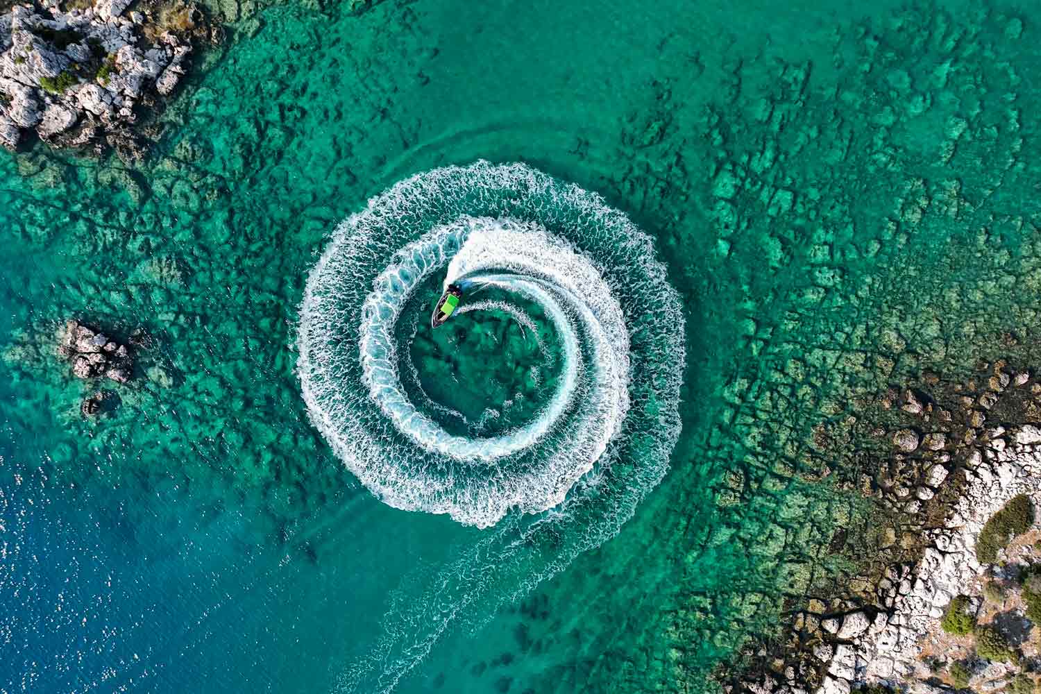 Aerial view of man driving a personal watercraft in the ocean creating a straight down circular pattern
