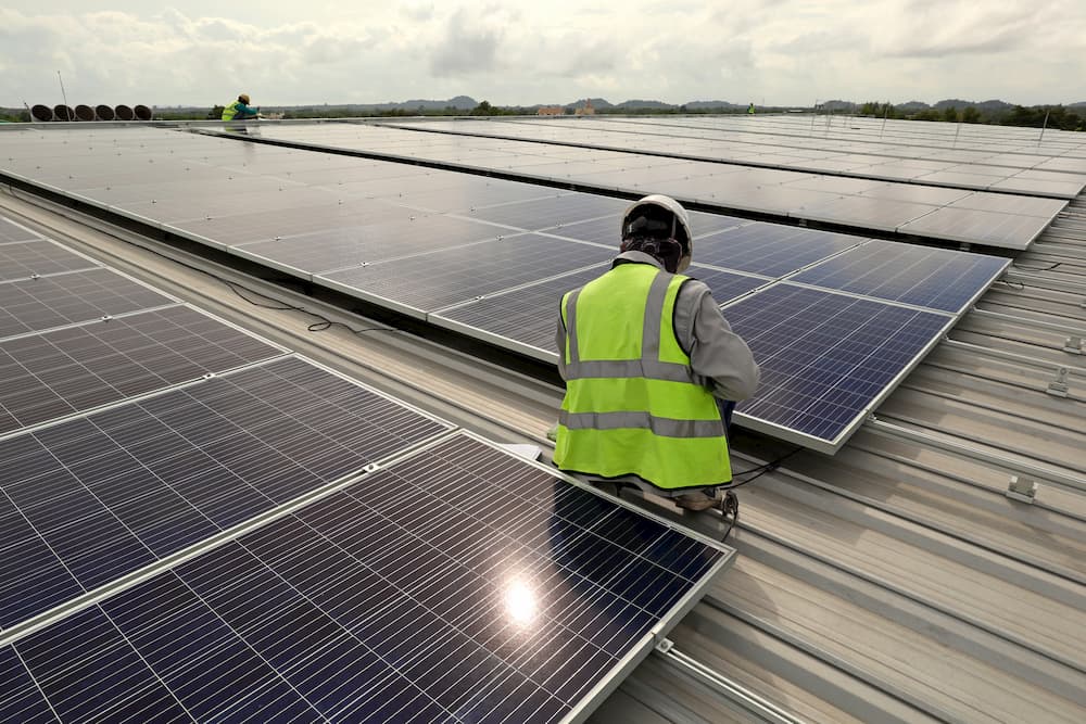 Worker seated on a rooftop with solar panels