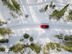 Aerial view of red car driving in the snow