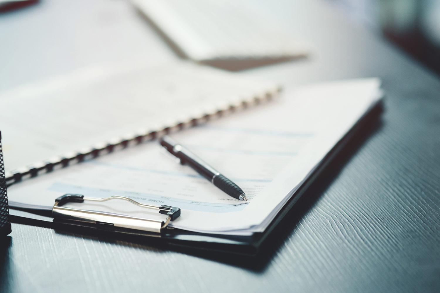Photo of a notebook and pen on an office desk.