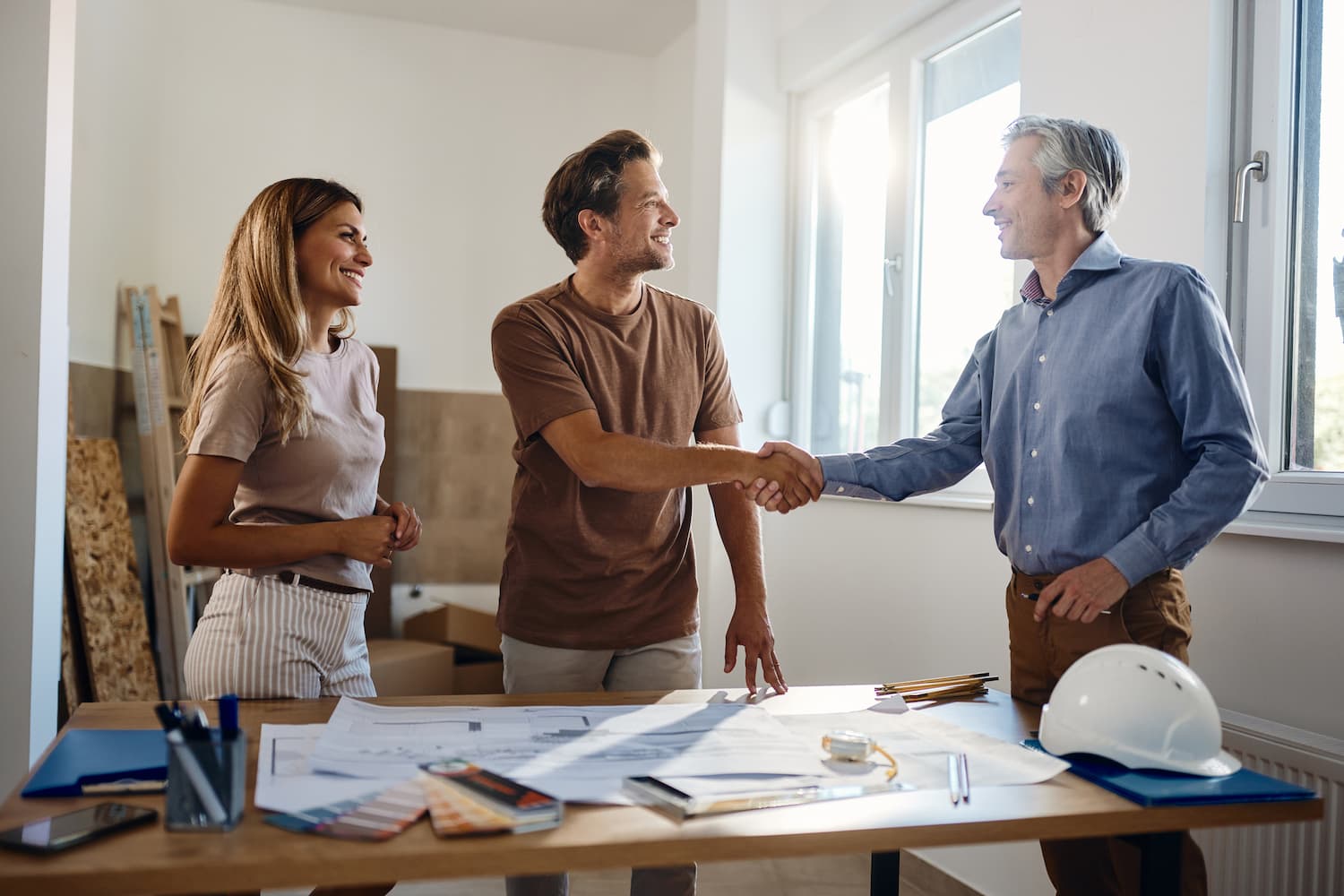 Happy couple shaking hands with an agent.