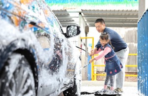 A father and his daughter washing a car
