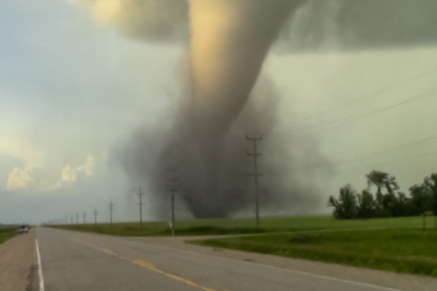 Tornado moving across field next to road.