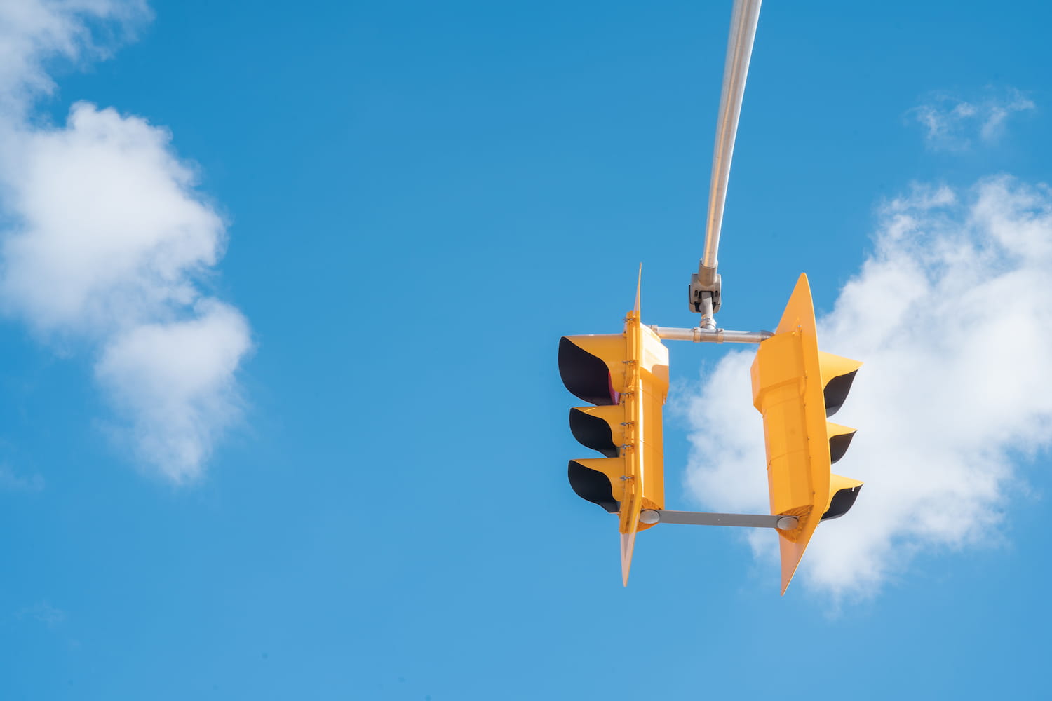 Yellow traffic light against the sky on a sunny day