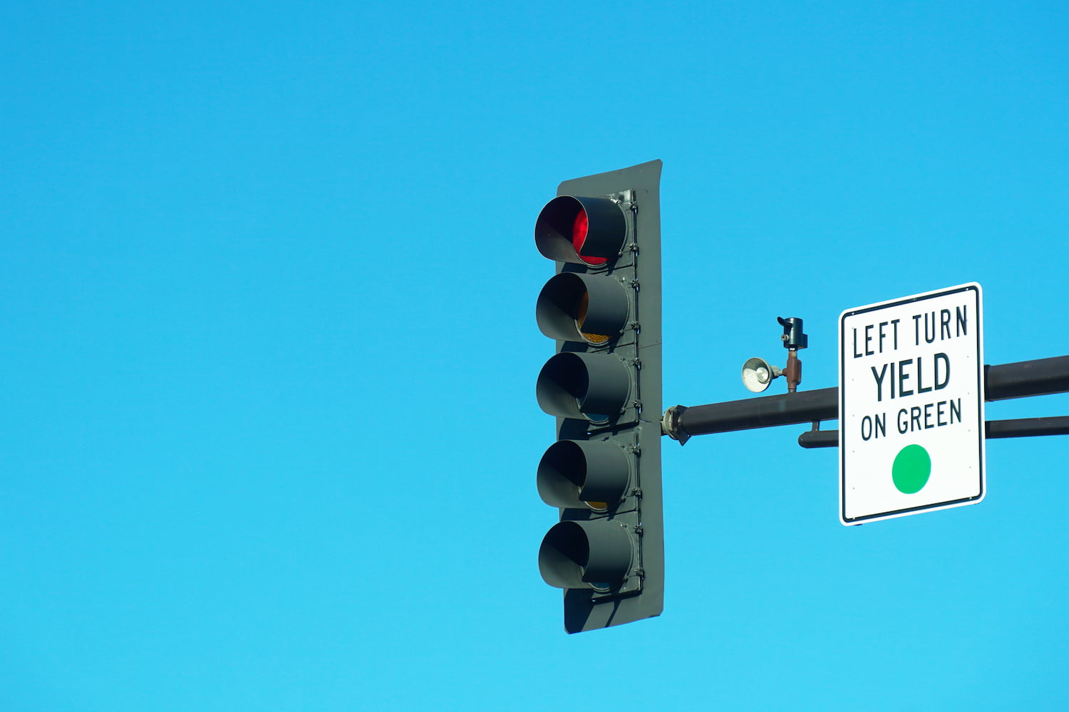 Red traffic light and "left turn yield on green" sign