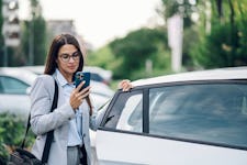 A woman in formal wear using her phone while getting out of her car