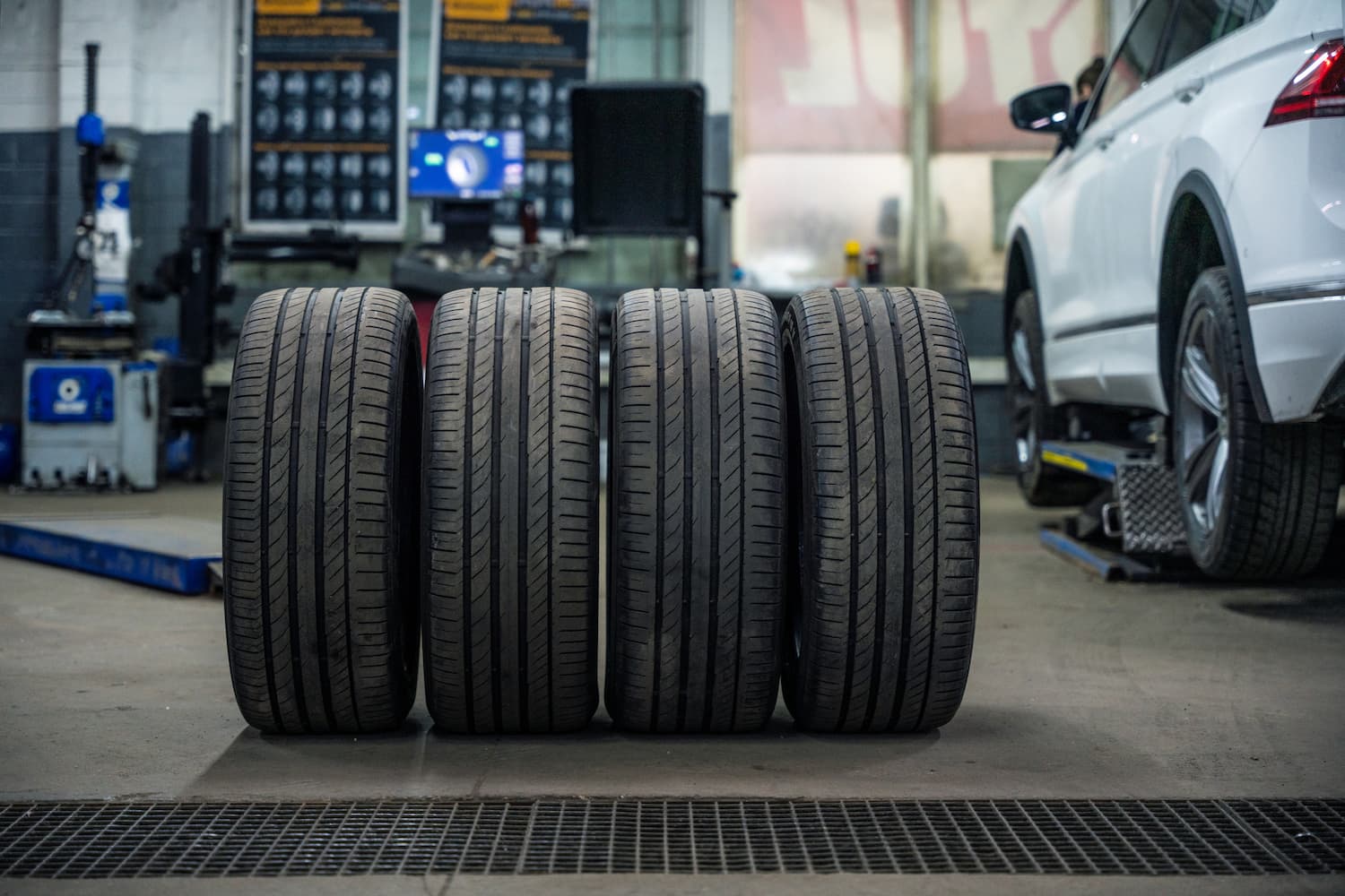Used and dirty tires at a service shop with a car on a lift.
