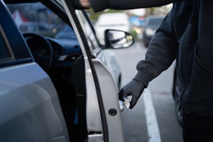 Close-up shot of a man wearing a black shirt and black gloves trying to open a car door