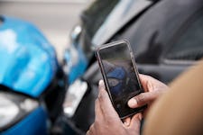 A closeup of a man's hands taking a photo with a phone of car collision