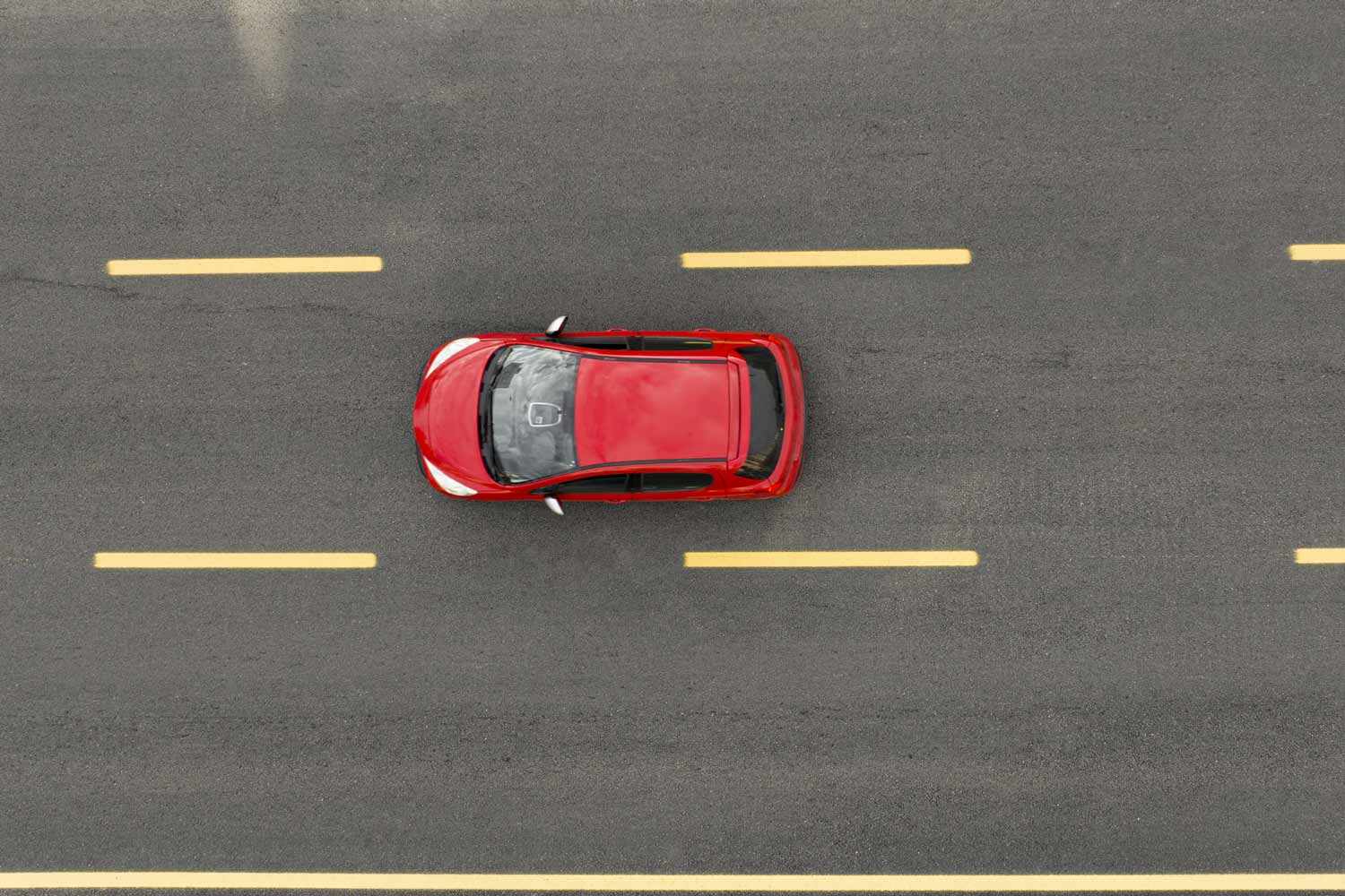 Red car on straight road from above.