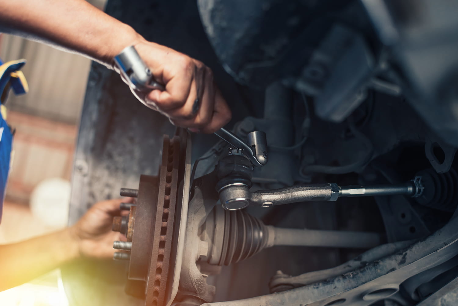 A car mechanic hand tightens the suspension of an elevated vehicle