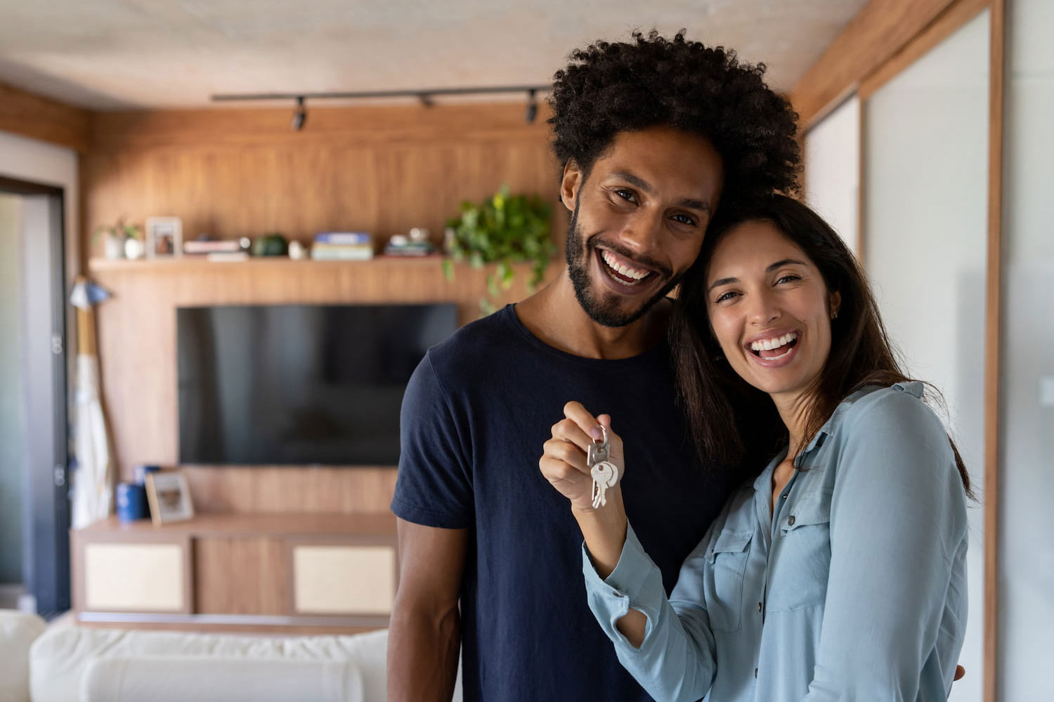 A happy couple holding the keys to their new home, smiling at the camera.