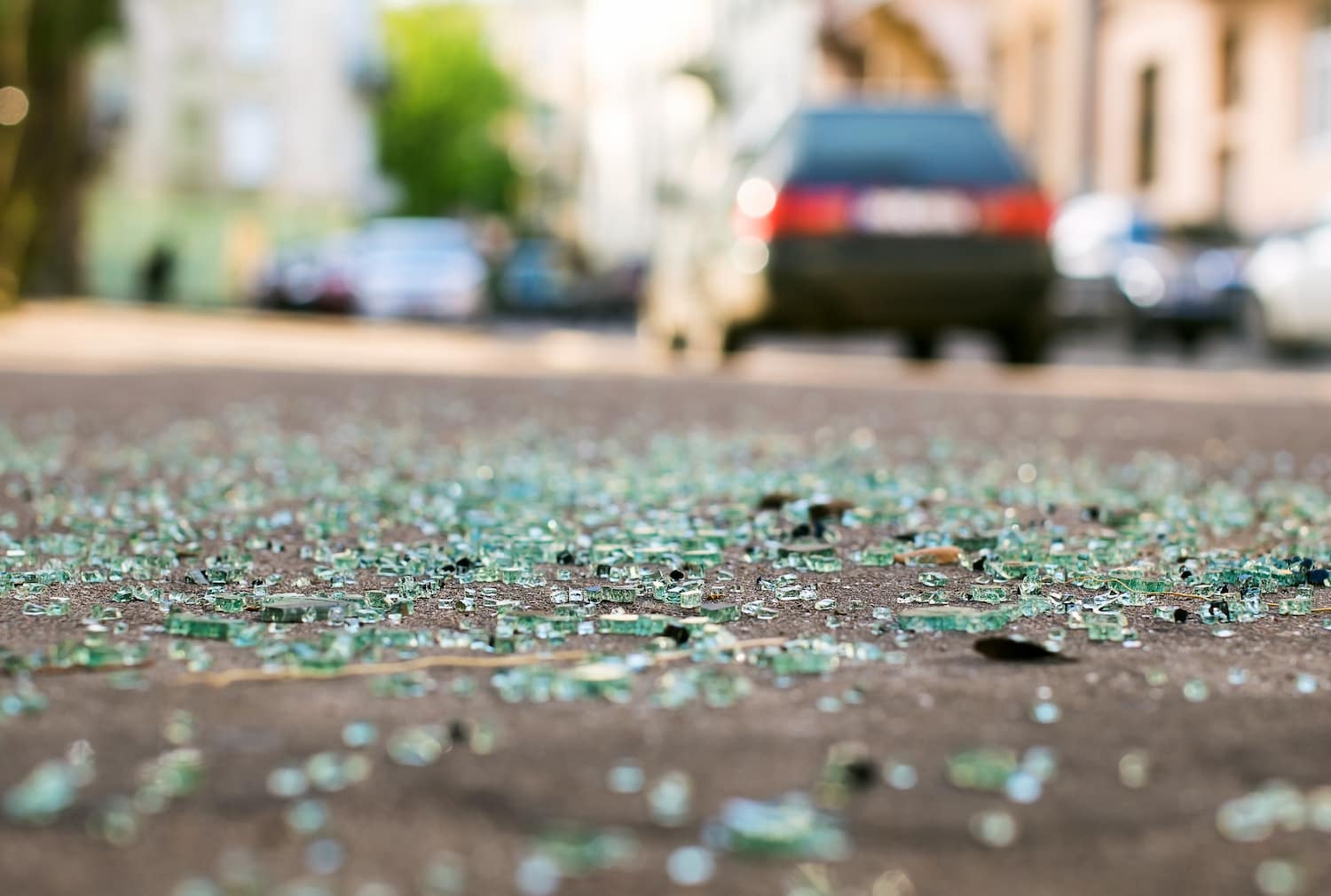 Shards of car glass on the street with a blurred background of a car on the road