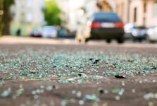 Shards of car glass on the street with a blurred background of a car on the road