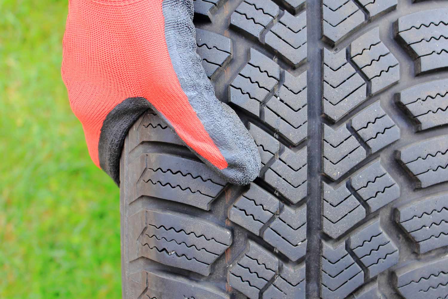Close up of gloved hand holding a winter tire.