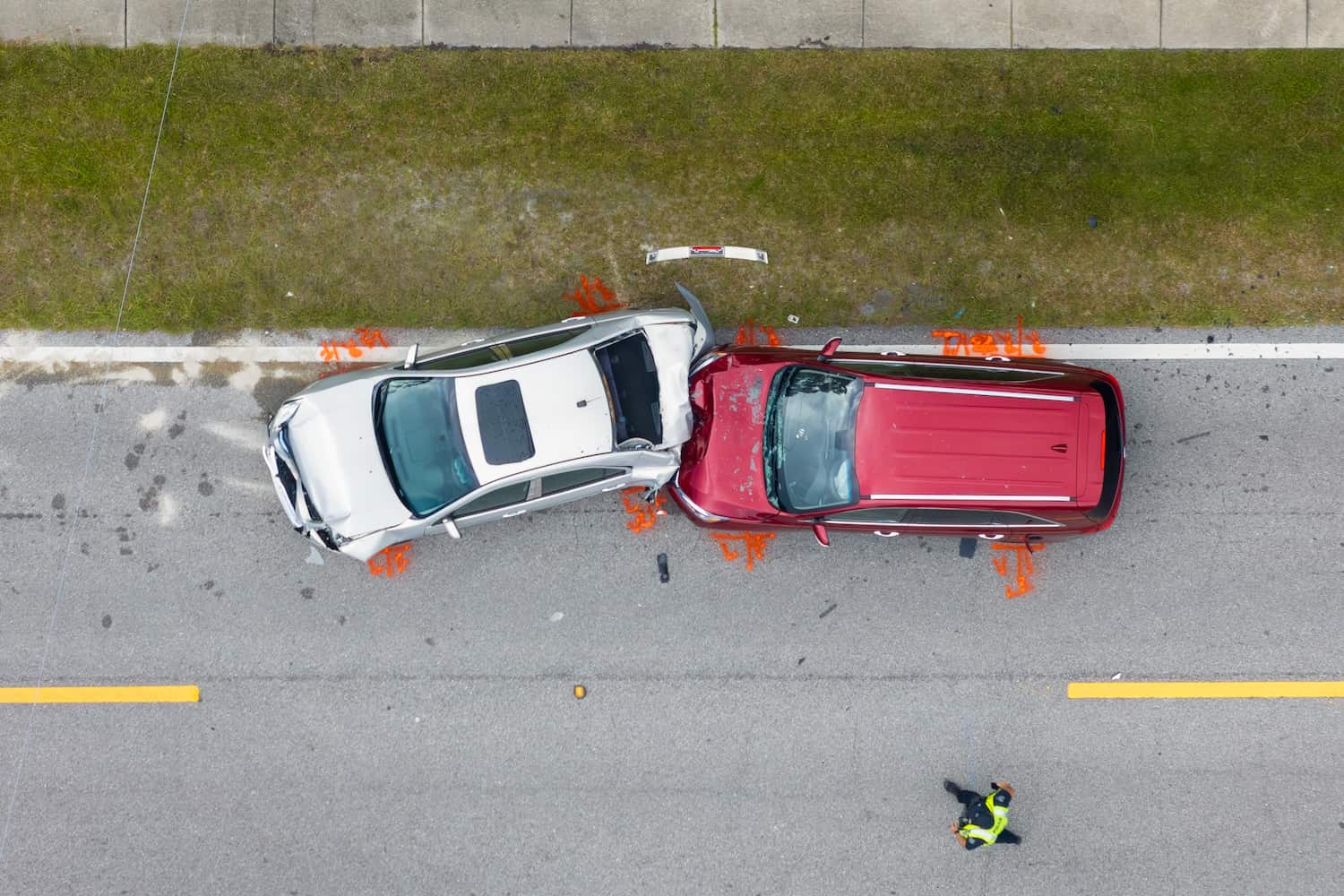 Aerial view of a silver car rear-ending a red SUV with a police officer on the scene.