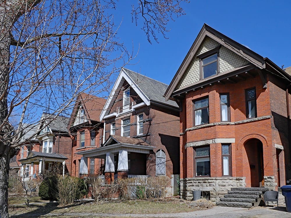 Brown townhouses located in a neighborhood, featuring bright and sunny weather.