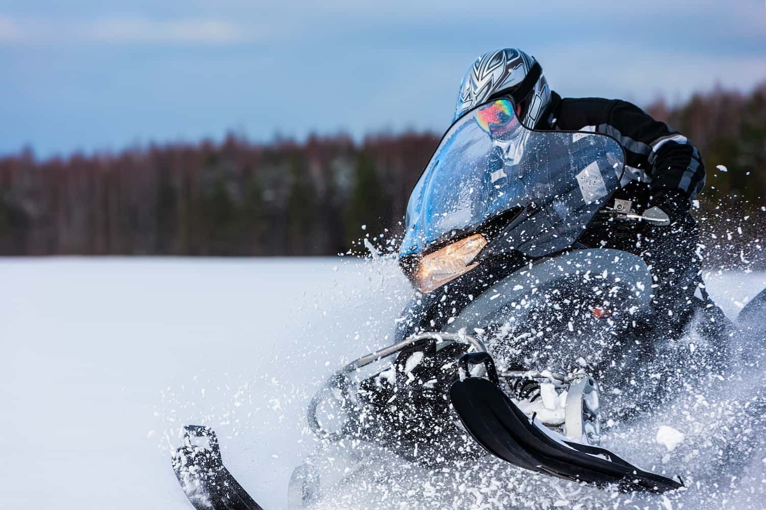 A snowmobile rider snow drifting on a sunny day.