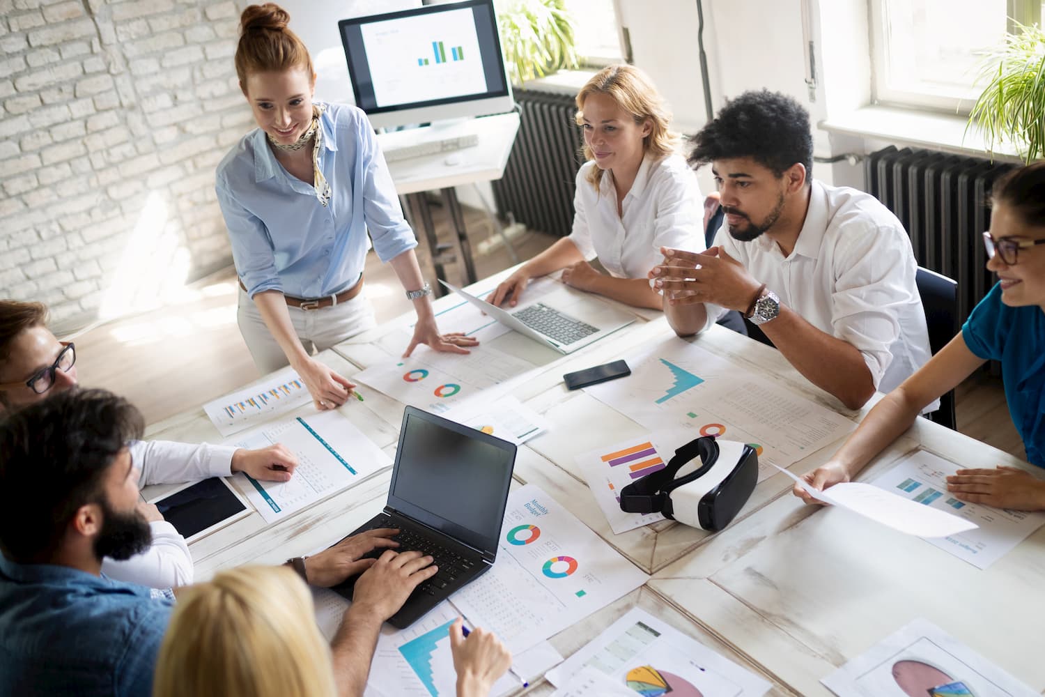 A group of employees discussing ideas while gathered around a table in a boardroom.
