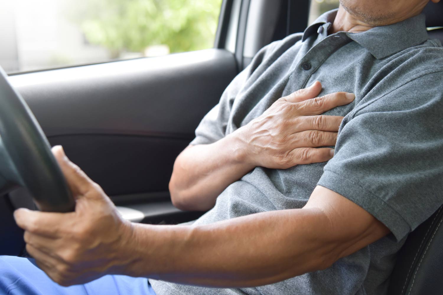 Someone places a hand on their chest while seated or behind the wheel.