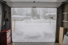 An open garage view to a snowy weather outside