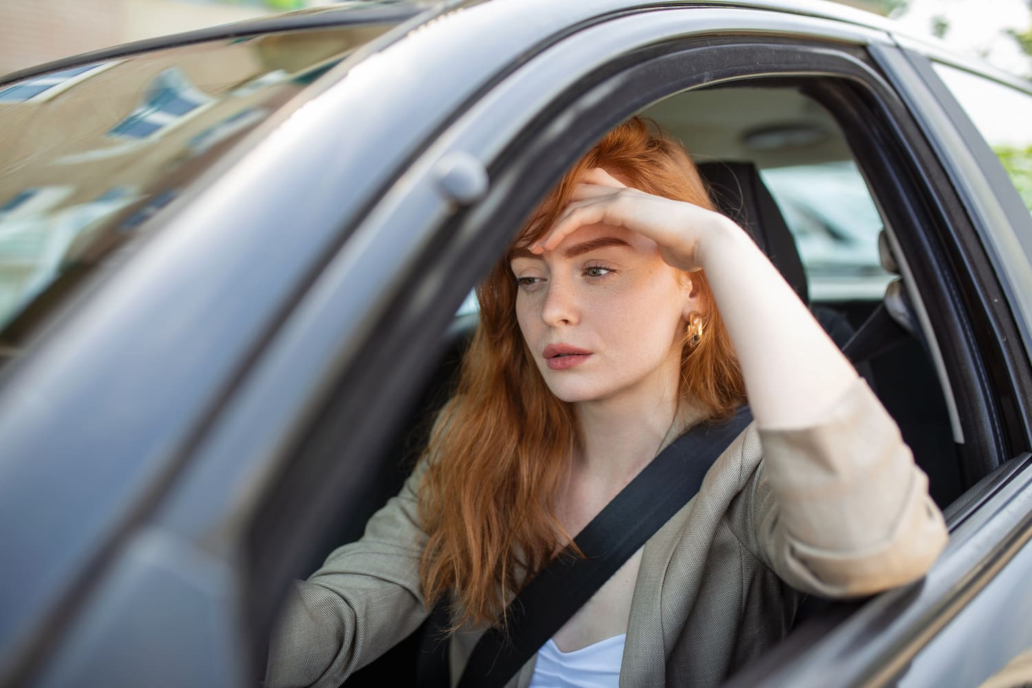 Nervous driver sits at wheel, has worried expression in a car by herself.